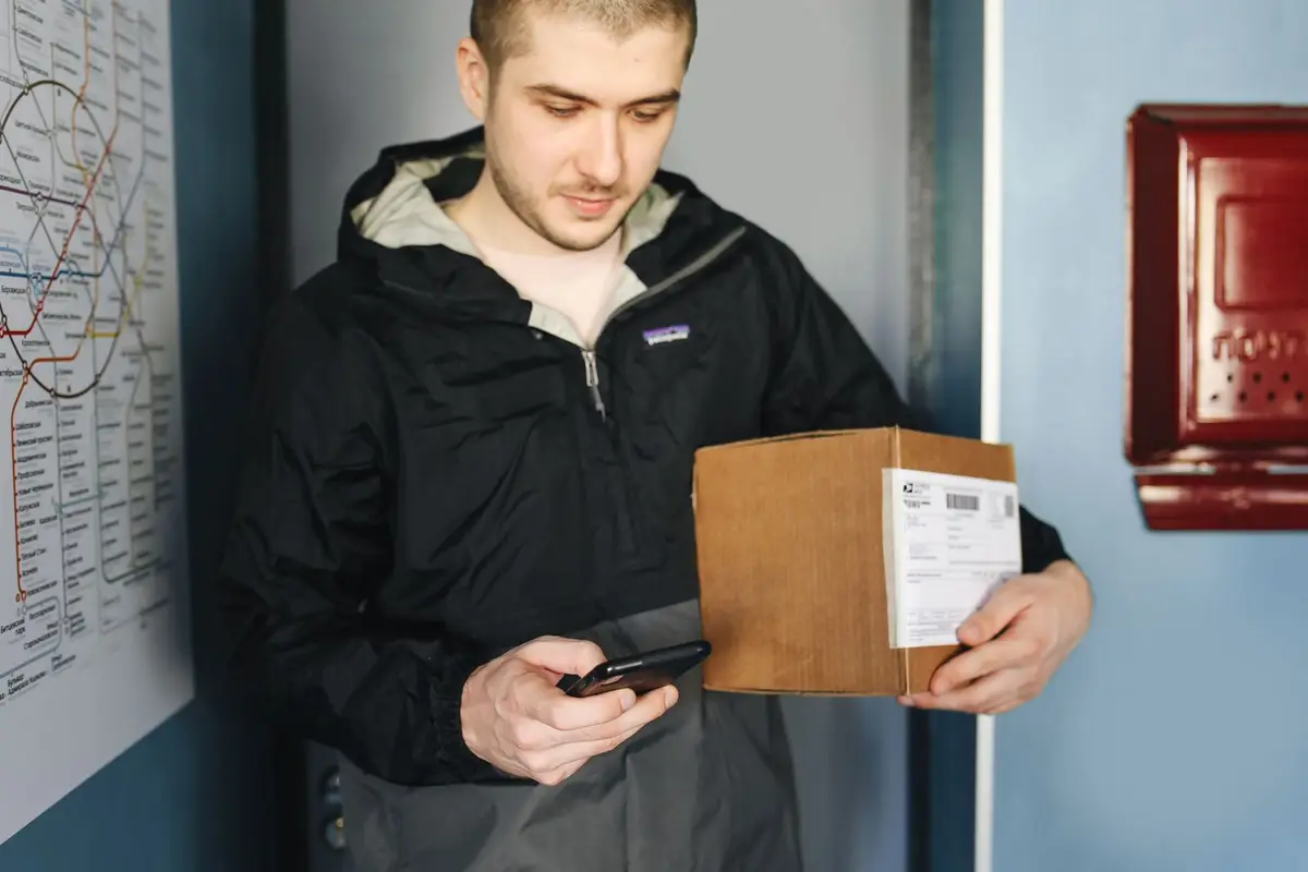 Продавец сканирует ярлык на посылке с помощью смартфона